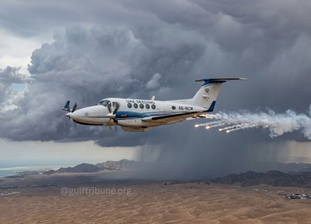 UAE Seedling turboprop plane flying over a desert with dark storm clouds, emitting smoke and flare trails from the rear.